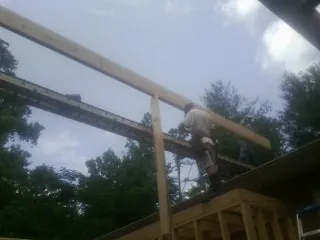 Carpenter setting a ridge beam over a new addition frame — Ice Dam Removal by Roofing Brothers in Whaleyville
