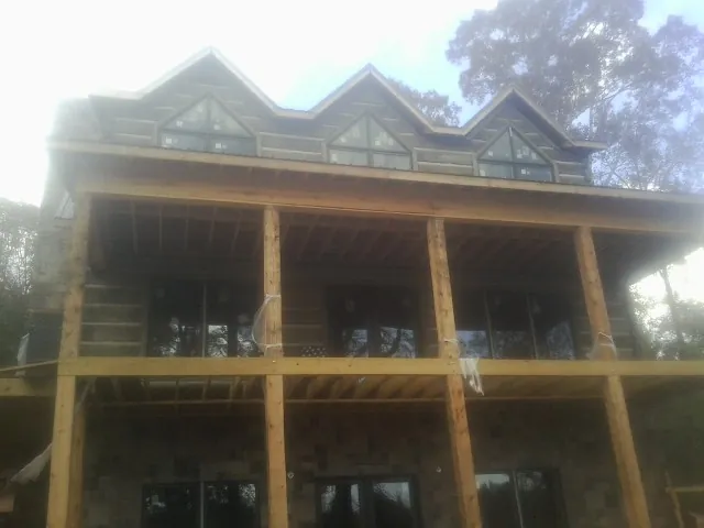 Dormers and porch framing on a large log home under construction — Roof Coating work by our crew in Whaleyville
