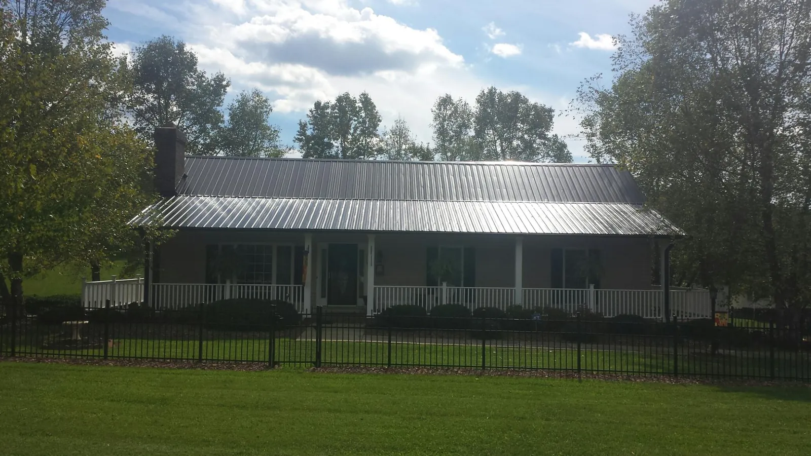 Gray metal roof on a brick ranch with a full width front porch — Gutter Guard Installation work by our crew in Whaleyville