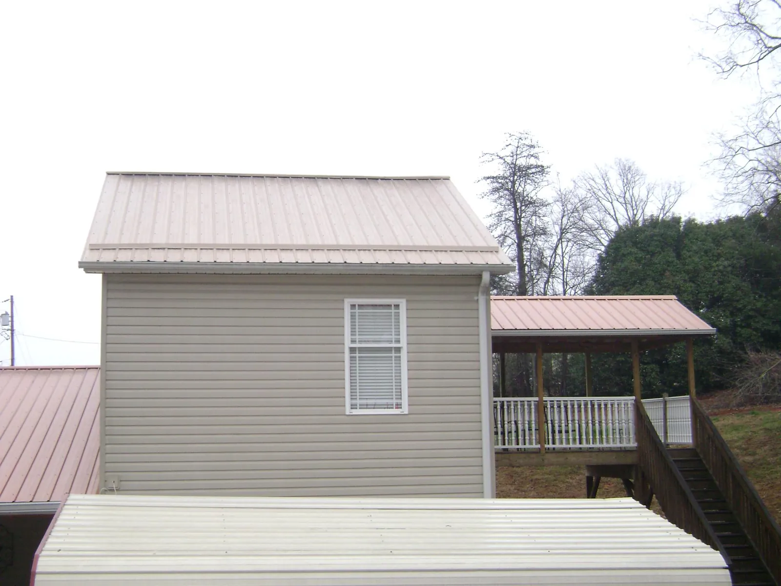 Tan metal roofs on a two story addition and attached porch, from a Roof Replacement job in Whaleyville
