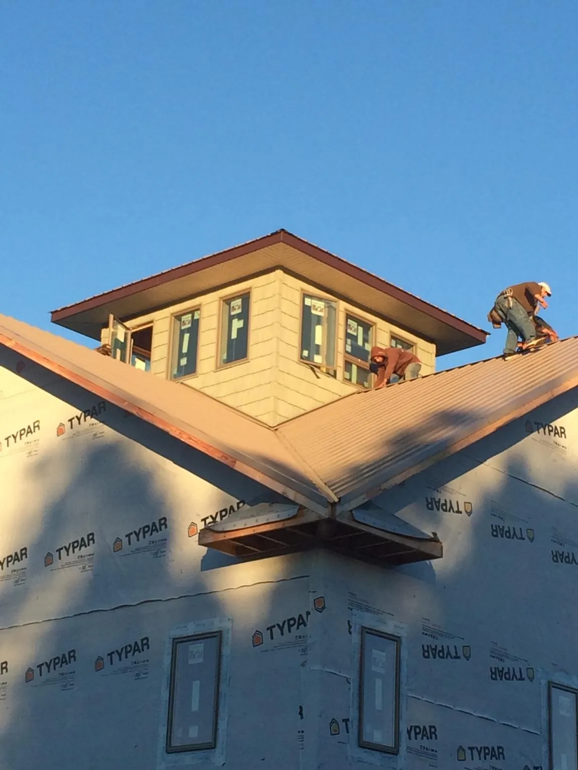 Roofers working around a rooftop cupola on a new metal roof at sunset — Roof Waterproofing in Whaleyville by Roofing Brothers